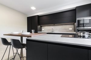 Cocina moderna negra con encimera porcelánica y barra de madera