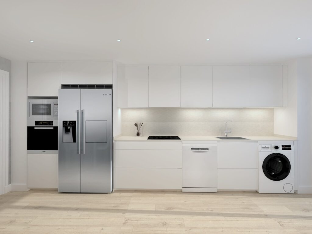 Esta cocina refleja un diseño moderno y minimalista, donde el color blanco predomina en los muebles y encimeras, creando un espacio luminoso y amplio. La distribución lineal y en paralelo optimiza la funcionalidad